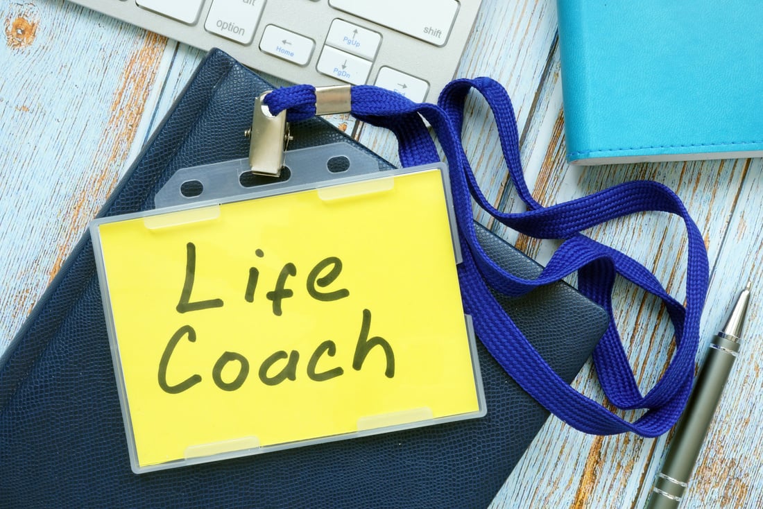 Life coach badge with keyboard on a wood.